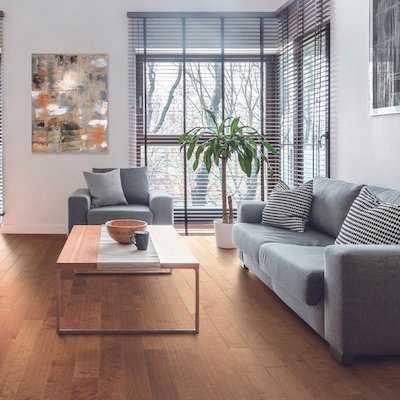 hardwood floors in a cozy minimalist living room with grey couches and large corner window